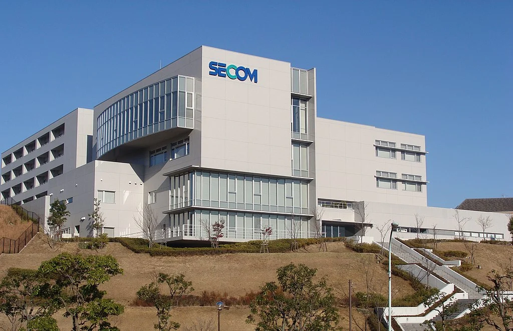 A expansive white office building with 'Secom' branded on the side.