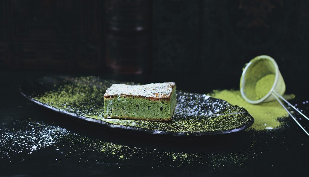 A green cake on a black dish.